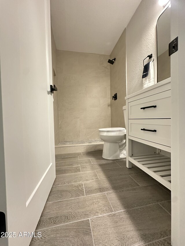 4902 S Fair Ln, Tempe, AZ 85282 - bathroom featuring toilet, tiled shower, wood finish floors, and vanity