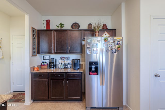 kitchen featuring light tile patterned floors, light stone counters, stainless steel refrigerator with ice dispenser, and dark brown cabinetry