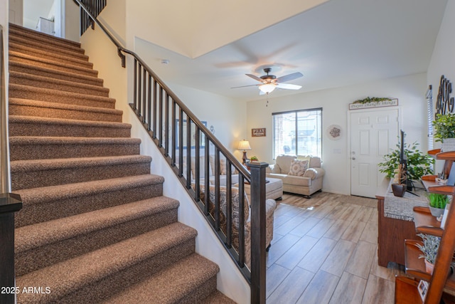 staircase featuring ceiling fan and hardwood / wood-style floors