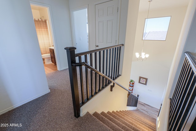 stairway with carpet floors and a chandelier