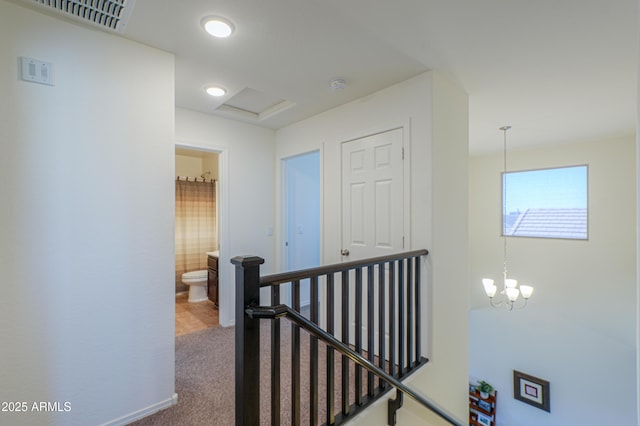 corridor with an inviting chandelier and carpet floors