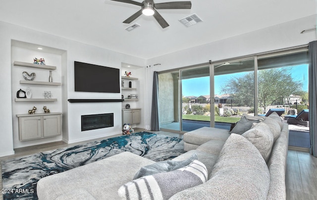 living room featuring light hardwood / wood-style floors, built in features, and ceiling fan