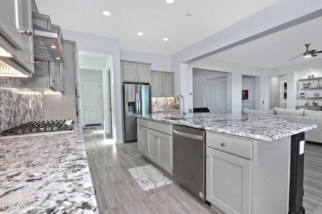 kitchen featuring decorative backsplash, a kitchen island with sink, sink, gray cabinets, and stainless steel appliances