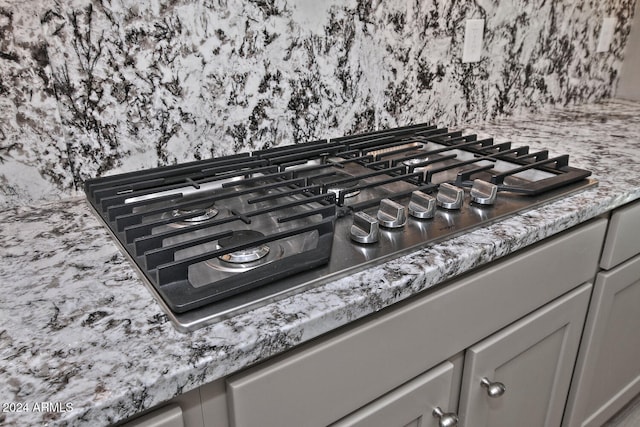 interior details with stainless steel gas stovetop, stone countertops, and gray cabinets