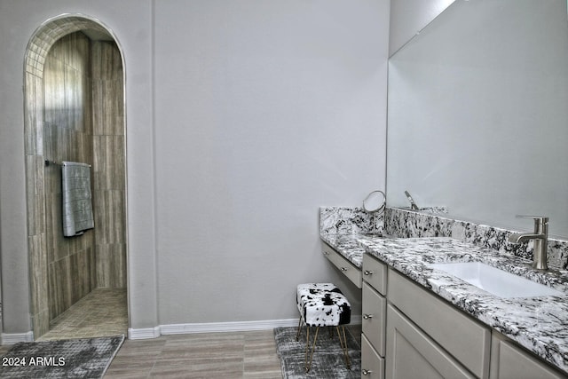 bathroom featuring vanity, a tile shower, and hardwood / wood-style flooring