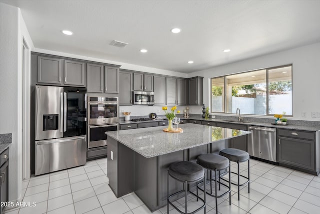 22341 N 100th Ln, Peoria, AZ 85383 - kitchen with stainless steel appliances, a kitchen island, light stone countertops, a sink, and a breakfast bar area