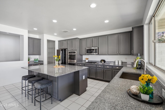 22341 N 100th Ln, Peoria, AZ 85383 - kitchen featuring appliances with stainless steel finishes, a sink, light stone counters, a center island, and a kitchen breakfast bar