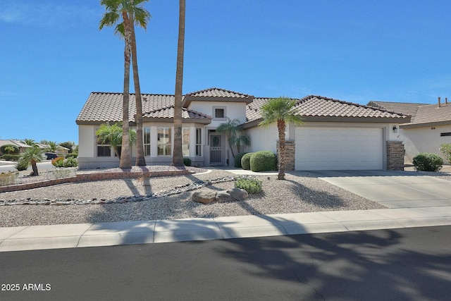 mediterranean / spanish home with driveway, a tile roof, a garage, and stucco siding