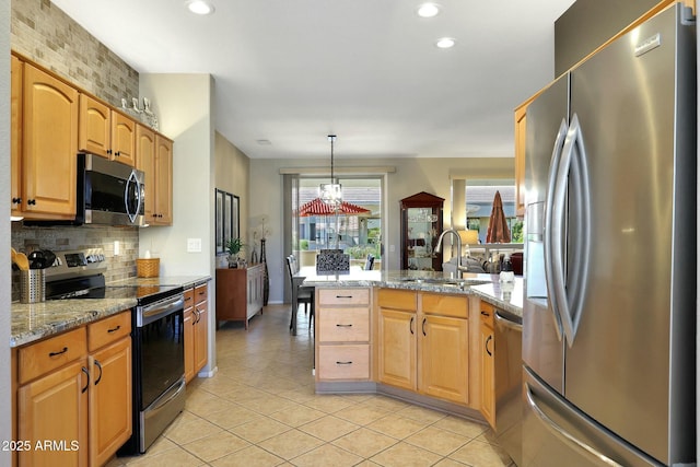 kitchen with decorative backsplash, a peninsula, light stone countertops, stainless steel appliances, and a sink