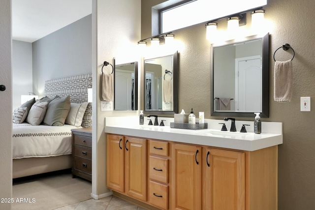 full bath featuring double vanity, a textured wall, tile patterned floors, ensuite bathroom, and a sink