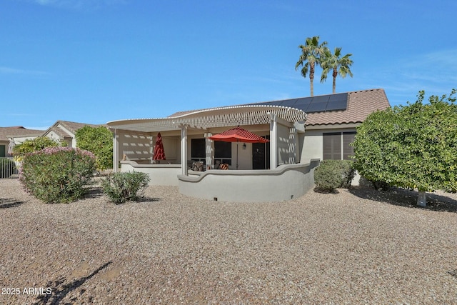 view of front of house with solar panels, stucco siding, a tile roof, and a pergola