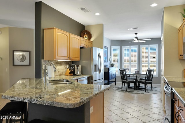 kitchen with light tile patterned floors, backsplash, appliances with stainless steel finishes, a sink, and a peninsula