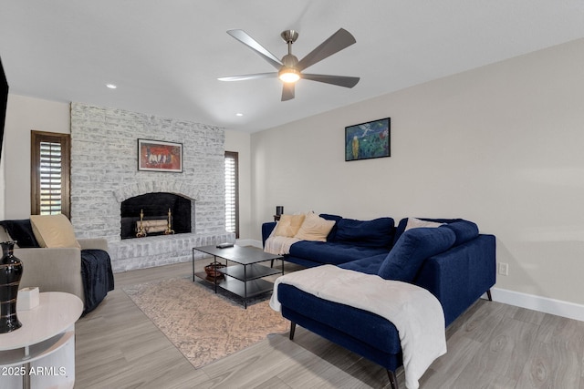 living room featuring a fireplace, ceiling fan, and light hardwood / wood-style floors