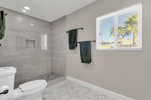 bathroom with toilet, tile patterned flooring, and a tile shower