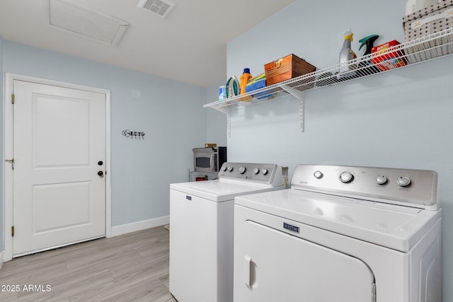 laundry area with washer and dryer and light hardwood / wood-style flooring