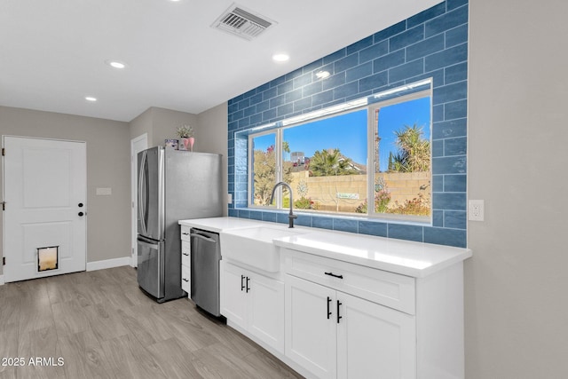 kitchen featuring appliances with stainless steel finishes, white cabinetry, light wood-type flooring, and sink