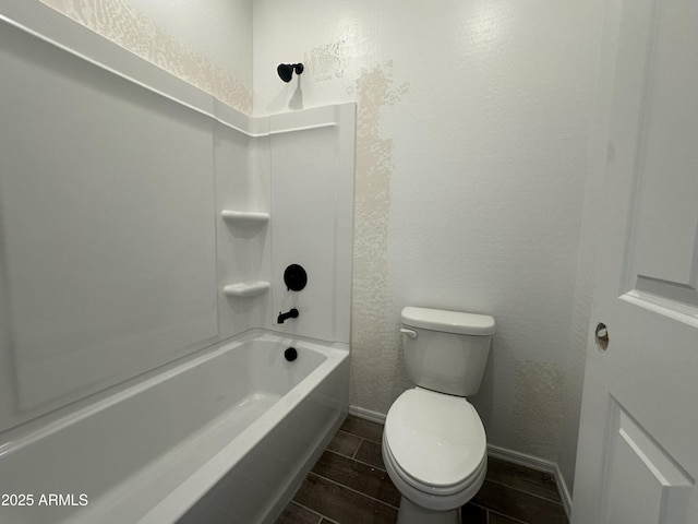 full bathroom featuring a textured wall, toilet, wood finish floors, and baseboards