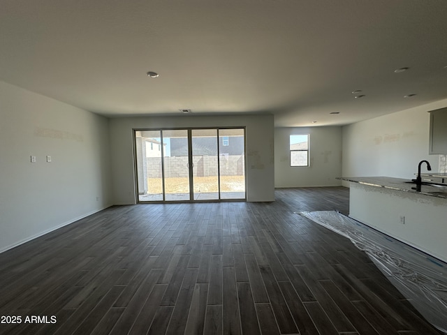 unfurnished living room with dark wood-style floors and baseboards