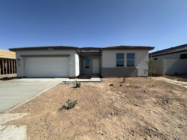 view of front facade featuring a garage, stucco siding, a tile roof, and concrete driveway