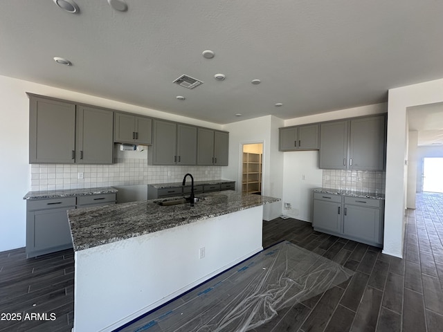 kitchen with dark wood-type flooring, gray cabinetry, a sink, and visible vents