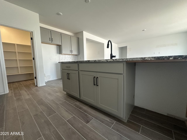 kitchen with tasteful backsplash, gray cabinets, recessed lighting, stone counters, and wood tiled floor
