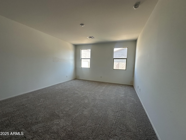 spare room featuring visible vents, light colored carpet, and baseboards
