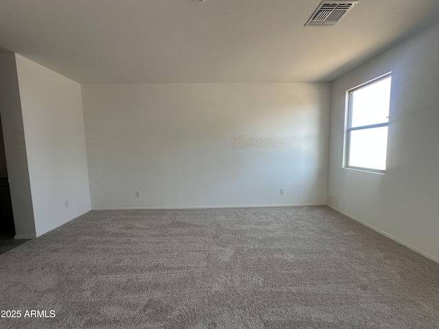 spare room with carpet flooring, visible vents, and baseboards