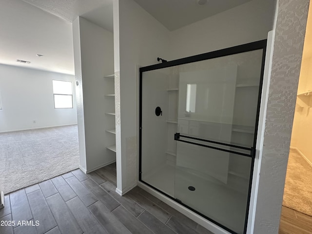 full bath featuring wood tiled floor, a stall shower, and baseboards