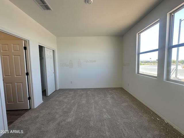 unfurnished bedroom featuring visible vents, multiple windows, carpet floors, and baseboards