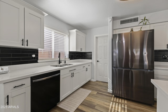 kitchen featuring white cabinetry, black dishwasher, and stainless steel fridge