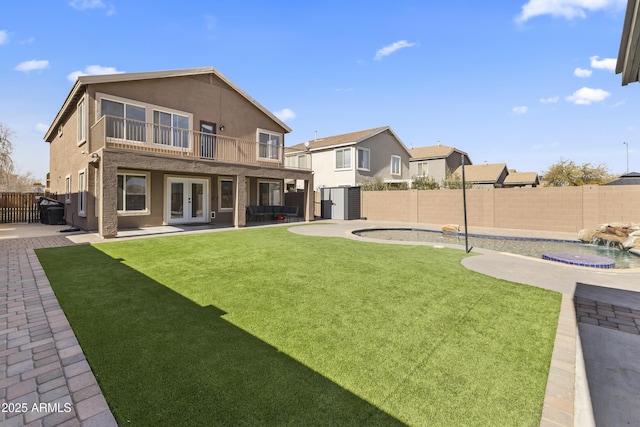 back of property with a fenced in pool, a patio, pool water feature, french doors, and a balcony