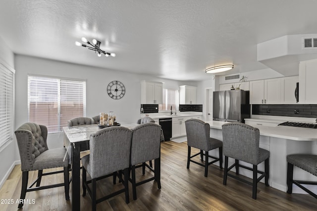 dining area with dark wood-type flooring, a notable chandelier, and a textured ceiling