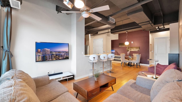 living room with ceiling fan, track lighting, wood-type flooring, and a high ceiling