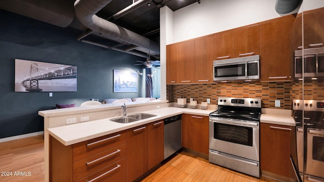 kitchen featuring sink, stainless steel appliances, tasteful backsplash, light hardwood / wood-style flooring, and kitchen peninsula