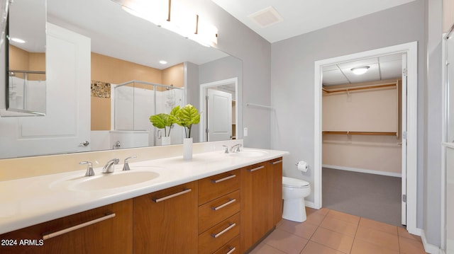 bathroom with tile patterned flooring, vanity, a shower with shower door, and toilet