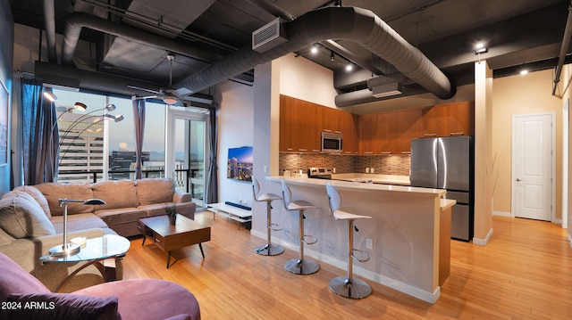 kitchen with ceiling fan, rail lighting, stainless steel appliances, a high ceiling, and kitchen peninsula