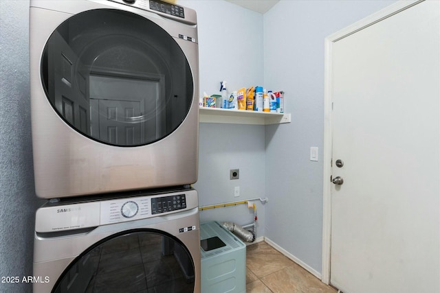 laundry room with tile patterned flooring, laundry area, baseboards, and stacked washer and clothes dryer