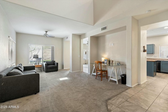 living room with light tile patterned floors, visible vents, light carpet, and baseboards