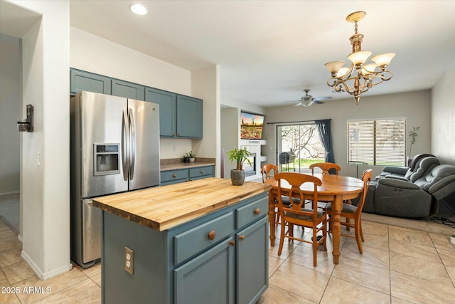 kitchen featuring ceiling fan with notable chandelier, wood counters, a kitchen island, open floor plan, and stainless steel fridge