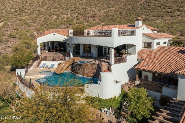 back of house with a swimming pool with hot tub and a patio area