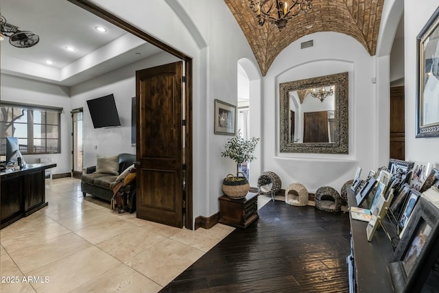 hallway featuring lofted ceiling, brick ceiling, and a chandelier