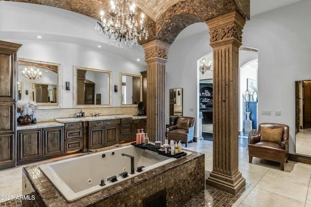 bathroom with vanity, vaulted ceiling, ornate columns, brick ceiling, and tiled bath