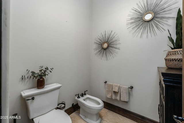 bathroom featuring tile patterned flooring, toilet, and a bidet