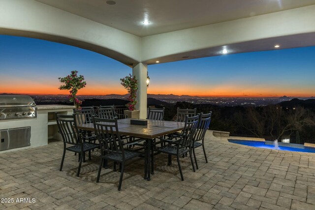 patio terrace at dusk with a mountain view, pool water feature, area for grilling, and a grill