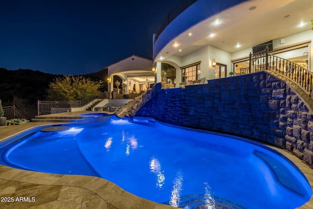 pool at night with an in ground hot tub