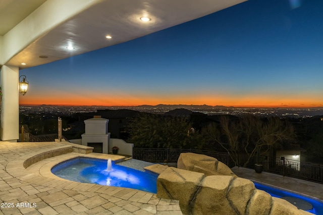 pool at dusk with an in ground hot tub and exterior fireplace