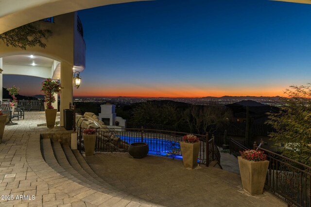 pool at dusk featuring a patio area and an outdoor fireplace