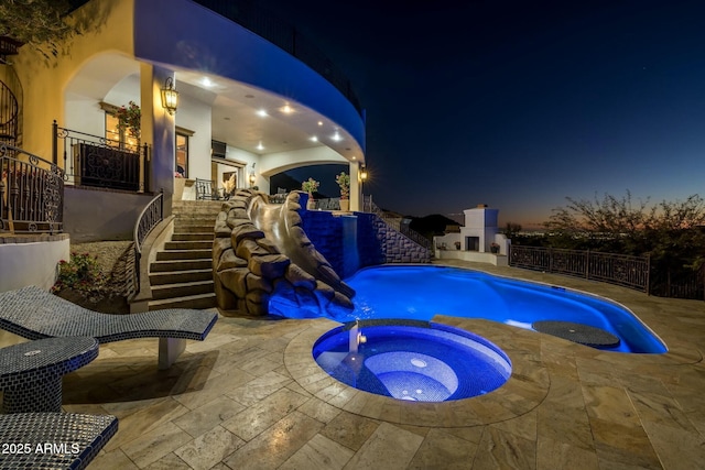 pool at twilight featuring an in ground hot tub and a patio