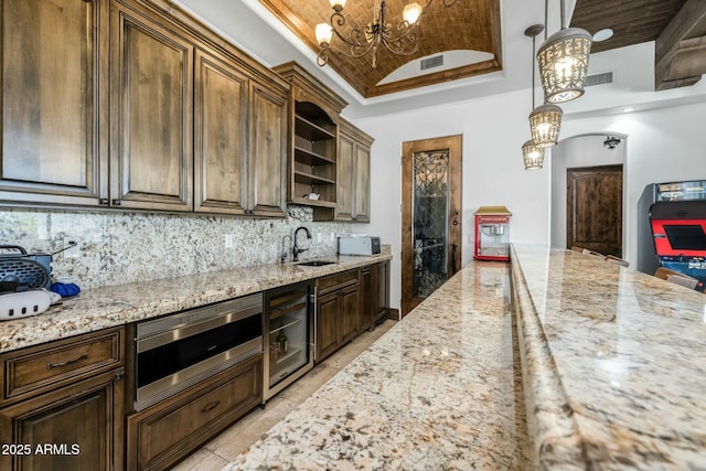 kitchen with wine cooler, vaulted ceiling, tasteful backsplash, decorative light fixtures, and brick ceiling