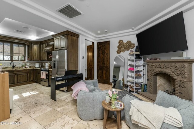 living room featuring a tray ceiling and sink